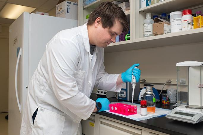 在一个研究实验室里，一个学生用管子把液体输送到一个容器里