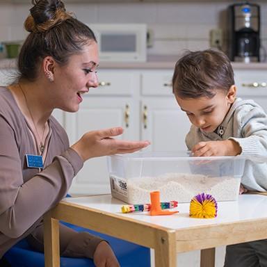 A U N E occupational therapy student works with a child at a sensory table