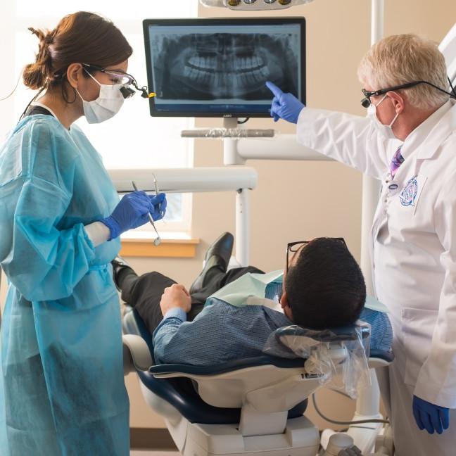 一名学生和教师在全球网络赌博平台口腔健康中心检查病人的牙科x光片